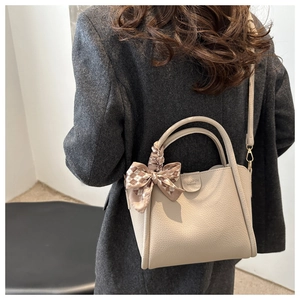 Détail du sac seau blanc cassé avec motif litchi, foulard décoratif et bandoulière