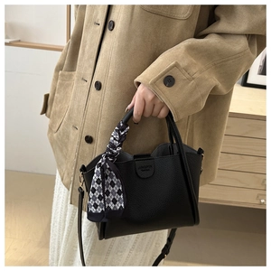 Detail of black lychee leather bucket bag with checkered silk scarf handle decoration