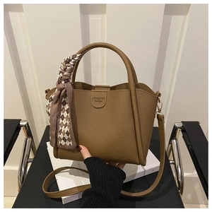 Close-up of brown litchi grain leather bucket bag with silk scarf and logo detail