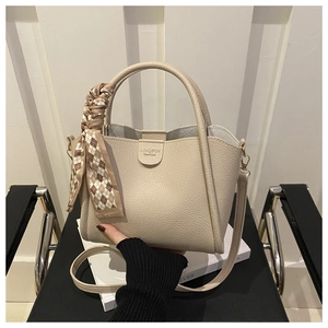 Close-up of beige lychee texture bucket bag with checkered silk scarf and shoulder strap