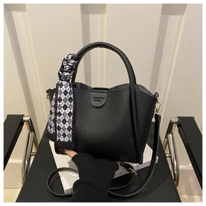 Close-up of black litchi grain leather bucket bag with decorative silk scarf on handle