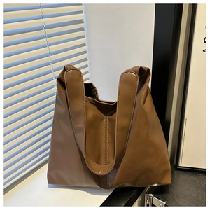 Close-up detail of smooth brown PU leather texture and wide strap of the large tote bag