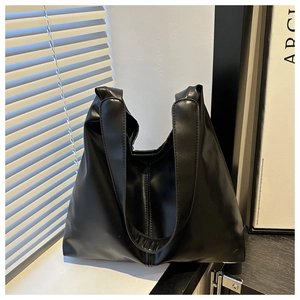 Detail of minimalist black PU leather tote bag with smooth texture and wide shoulder strap