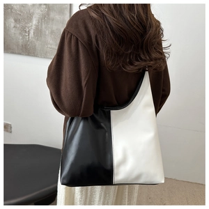 Detail of minimalist black and white color-block tote bag in glossy patent leather finish