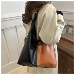 Detail of two-tone black and caramel tote bag with smooth faux leather texture