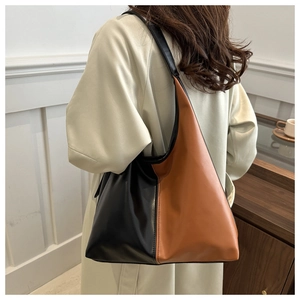 Detail showing the two-tone black and brown leather texture and wide shoulder strap