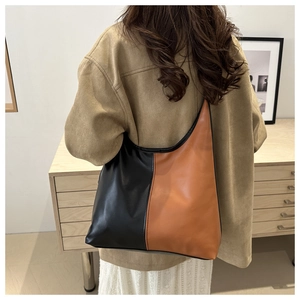 Detail of color-block tote bag in black and brown leather worn over the shoulder