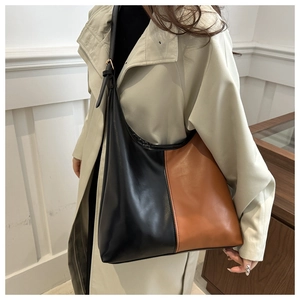 Close-up of a large two-tone patchwork tote bag in black and caramel brown leather