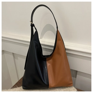 Detail of black and brown leather tote bag showing adjustable strap and gold metal hardware