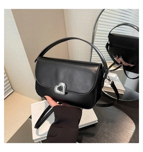 Detail of black leather saddle bag featuring a silver hollow heart buckle and straps