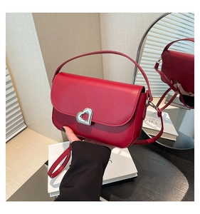 Close-up of red leather saddle bag featuring a silver heart-shaped metal twist lock