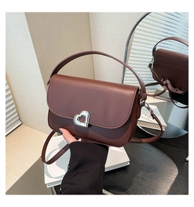 Detail of brown matte leather shoulder bag with a silver heart-shaped metal buckle