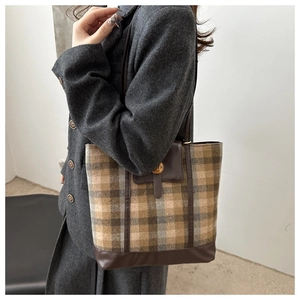Detail of vintage plaid tote bag with brown leather trim and golden metal clasp
