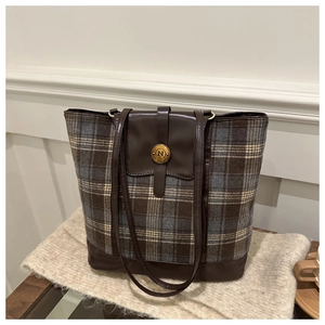 Close-up of tartan pattern tote bag with vintage brown leather trim and metallic N buckle