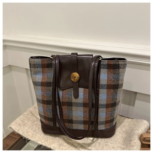 Close-up of retro plaid pattern fabric and brown leather handle on large tote bag
