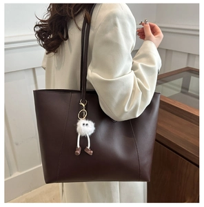 Detail view of large dark coffee tote bag featuring a white plush keychain ornament