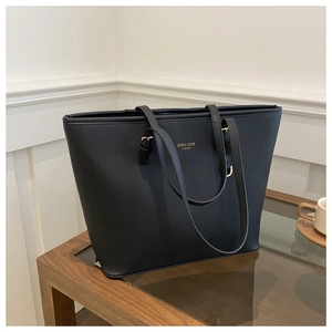 Primer plano de bolso tote de cuero negro texturizado con letras doradas y asa ajustable
