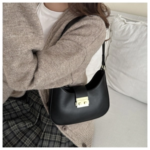Detail of black leather crescent bag with a polished gold metallic buckle closure