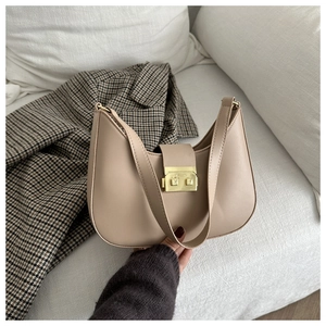Detail of a beige half-moon hobo bag with a stylish gold rectangular lock and wide strap