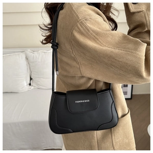 Detail of black leather underarm bag with knot strap and Fashion & Bags gold lettering