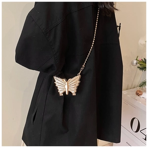 Détail d'un sac de soirée papillon doré avec strass et bandoulière en chaîne perlée