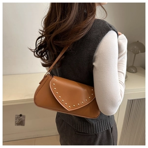 Close-up of caramel brown PU leather shoulder bag with golden rivet stud details