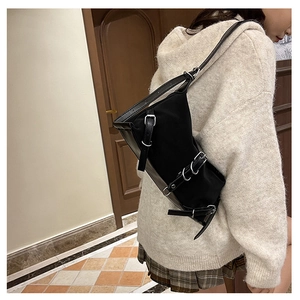 Close-up of a black nylon crossbody bag with metal buckles worn by a female model