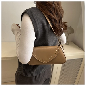 Close-up of vintage brown underarm bag with gold rivet V-pattern on high-quality faux leather
