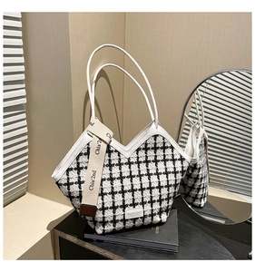 Detail of tweed checkered tote bag with white leather trim and decorative ribbon strap