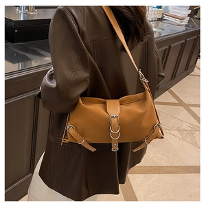 Detail view of caramel shoulder bag with silver metal buckles and adjustable straps