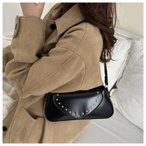 Detail of black leather underarm bag with gold rivet studs worn by a model