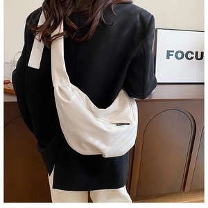 Back view of model wearing a white half-moon crossbody bag with wide shoulder strap