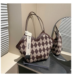 Detail of quilted tote bag with V-shaped opening and brown leather handles