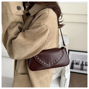 Detail of a vintage dark brown underarm bag with gold studs and matte leather texture