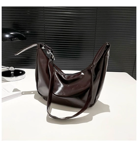 Detail of dark brown glossy hobo bag featuring polished texture and adjustable strap