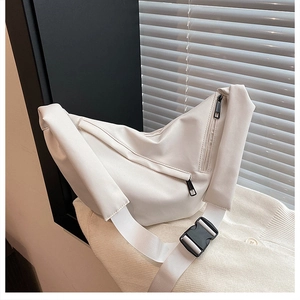 Detail of minimalist cream crossbody bag with metal zipper and adjustable buckle strap