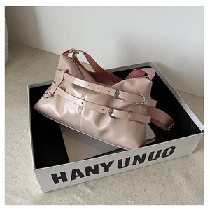 Detail of minimalist beige pink glossy PU leather bag with silver buckle and nylon strap