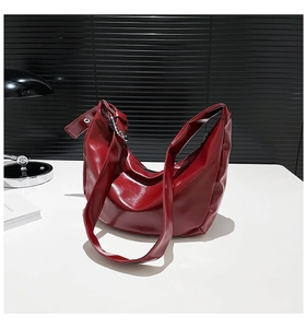 Detailed view of burgundy crescent hobo bag with glossy pleated leather and silver buckle