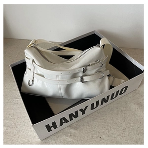 Detail of white glossy patent leather shoulder bag with metal buckles and silver rings