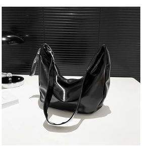 Detail of glossy black moon-shaped crossbody bag with polished PU leather and silver eyelets