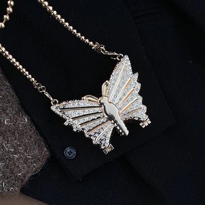 Élégant collier pendentif papillon doré avec strass sur une veste de costume noire