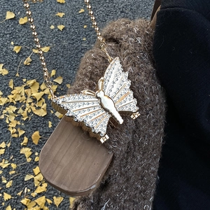 Sac papillon élégant avec diamants blancs et chaîne dorée sur un pull d'automne