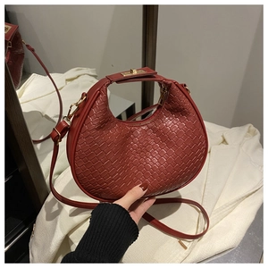 Detail of red woven crescent bag with gold hardware and long leather shoulder strap