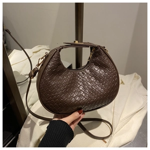 Detailed view of woven texture and metal zipper on brown crescent hobo handbag
