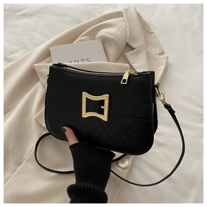 Détail du sac bandoulière matelassé noir avec fermoir doré sur un blazer beige