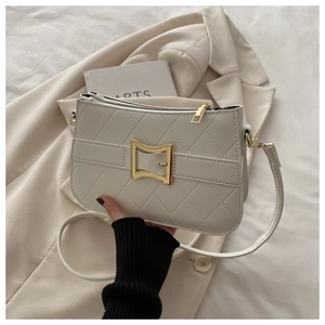 Détail de la pochette matelassée crème avec boucle dorée en nœud et bandoulière