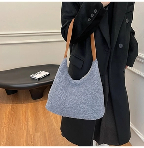 Detail of soft fuzzy light blue tote bag with brown leather strap on black coat