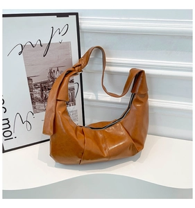 Detailed macro shot of brown pleated shoulder bag with decorative strap knot and silver zipper