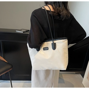 Detail view of large waterproof tote bag with black shoulder straps and leather patch