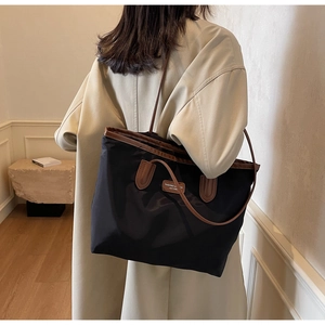 Detailed view of spacious black nylon tote bag with leather trim on model shoulder